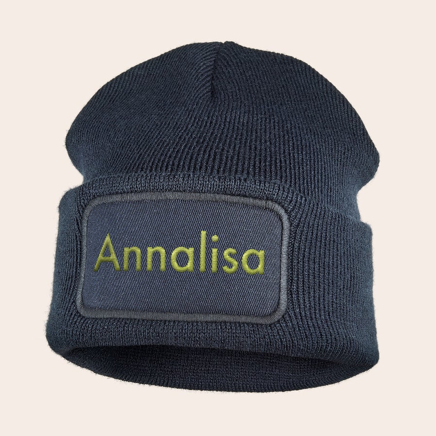Cappello ricamato Berretto blu scuro in maglia con risvolto, ricamato con il nome Annalisa in giallo.