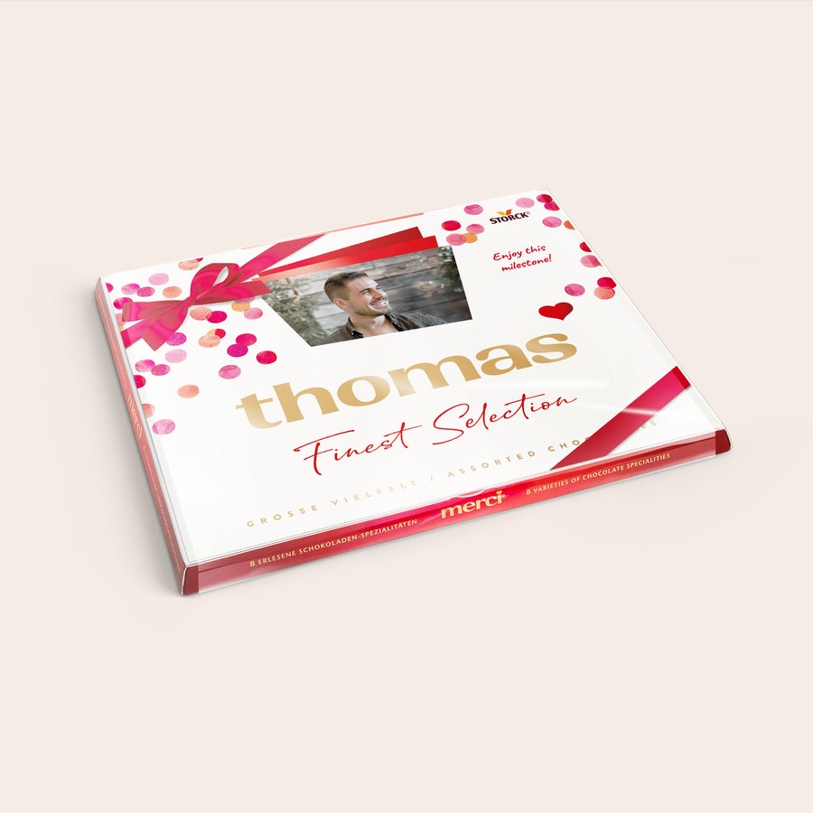 Čokoláda merci Finest Selection s kartičkou Čokoláda Merci s personalizovanou kartou – 250 gramov s menom Thomas a fotkou muža, doplnená ružovou stuhou a konfetami na obale.