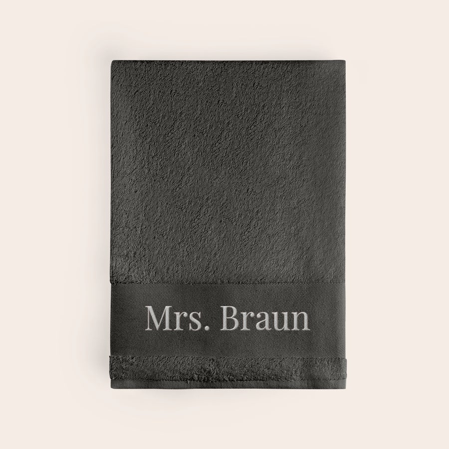 Badetuch mit Namen Personalisiertes anthrazitfarbenes Handtuch mit dem Namen "Mrs. Braun" in Hellgrau eingestickt, um etwas Besonderes aus einem alltäglichen Gegenstand zu machen.