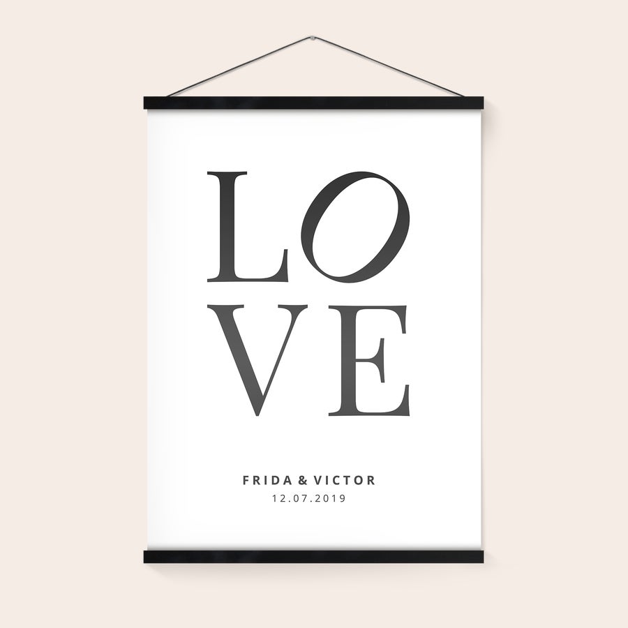 Personliggjort plakat med ophæng af træ En personlig plakat med et praktisk magnetisk plakatophæng, printet med teksten LOVE, navnene Frida & Victor og datoen 12.07.2019.