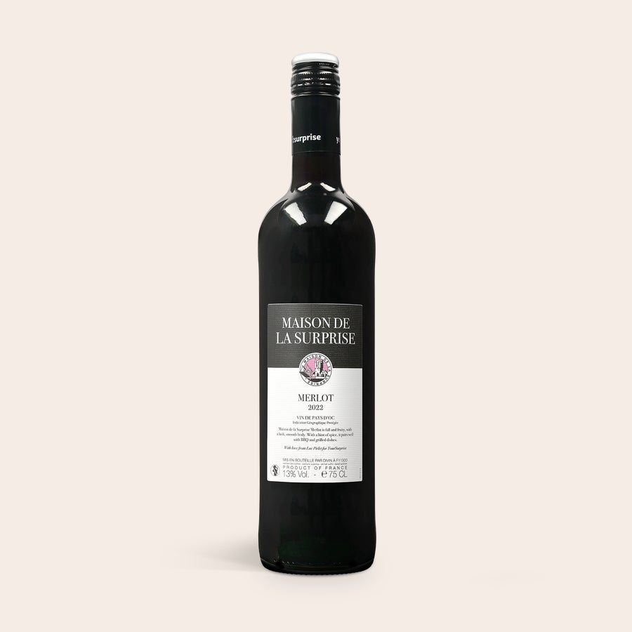 Personlig vin Maison de la Surprise Cabernet Sauvignon Merlot vinflaska med etikett "Maison de la Surprise Merlot 2022" för personlig graverad vinlåda