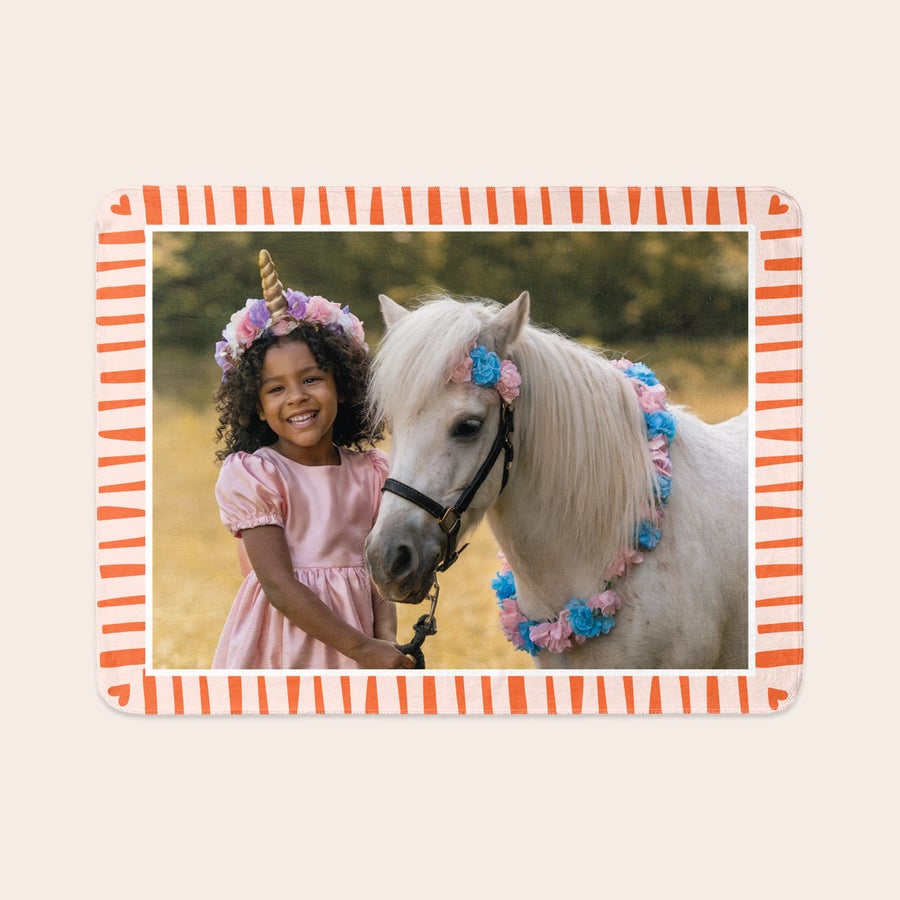 Fleecetæppe med billede Et personaliseret fotoprint fleece tæppe med et billede af en pige og pony, indrammet med et stribet mønster, så din sofa vil være super hyggelig.