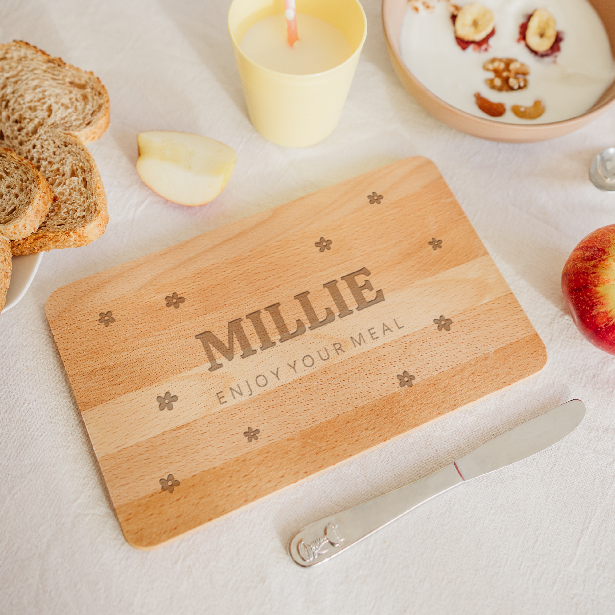 Wooden bread board engraved with the name Millie and text Enjoy Your Meal, customized with flower designs.