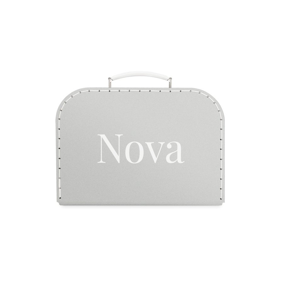 Tryckt barnresväska Leksaksväska i grått med vit handtag, tryckt med namnet Nova. En resesällskap som är unikt deras.
