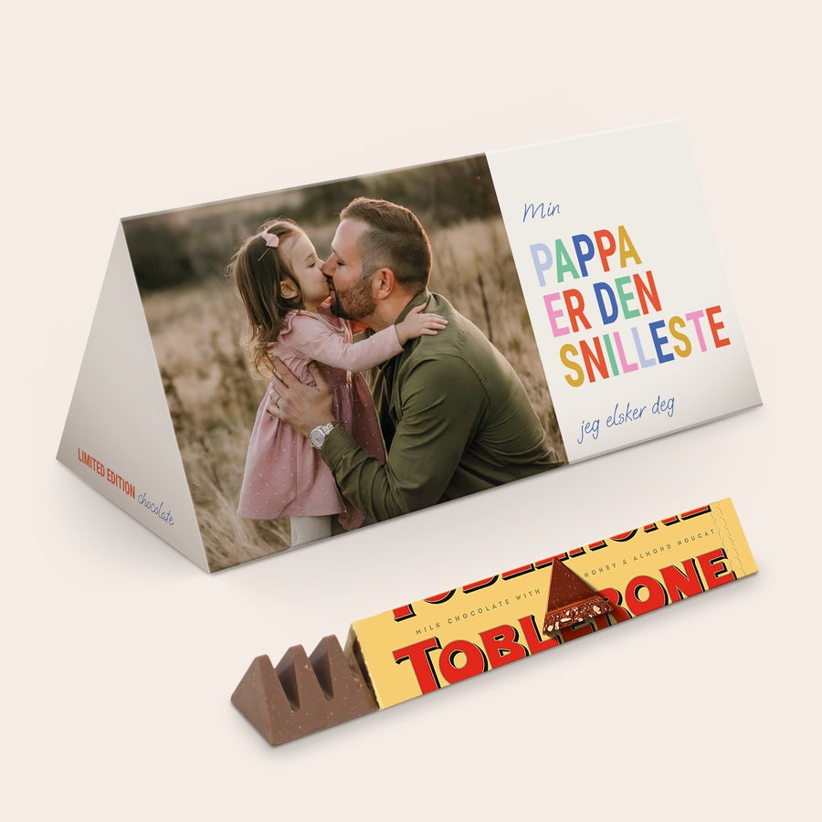 Toblerone med navn XL Toblerone Selection sjokoladebar med personlig bilde av far og datter, trykt tekst "Min pappa er den snilleste jeg elsker deg" og "Limited edition chocolate", ved siden av en åpen melkesjokolade Toblerone med honning- og mandelnougat.