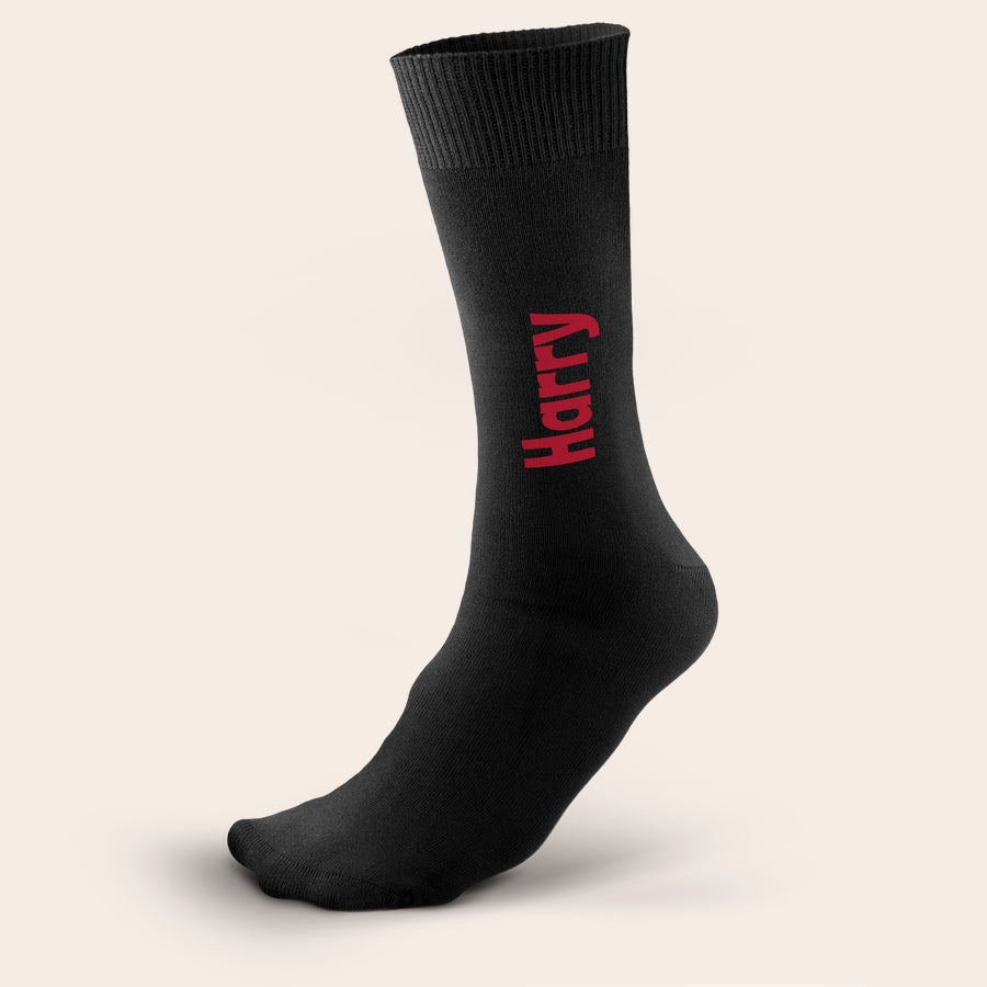 Calcetines con nombre Calcetín negro con el nombre "Harry" impreso en rojo, personalizable con tu propio texto para diseñar los calcetines personalizados.