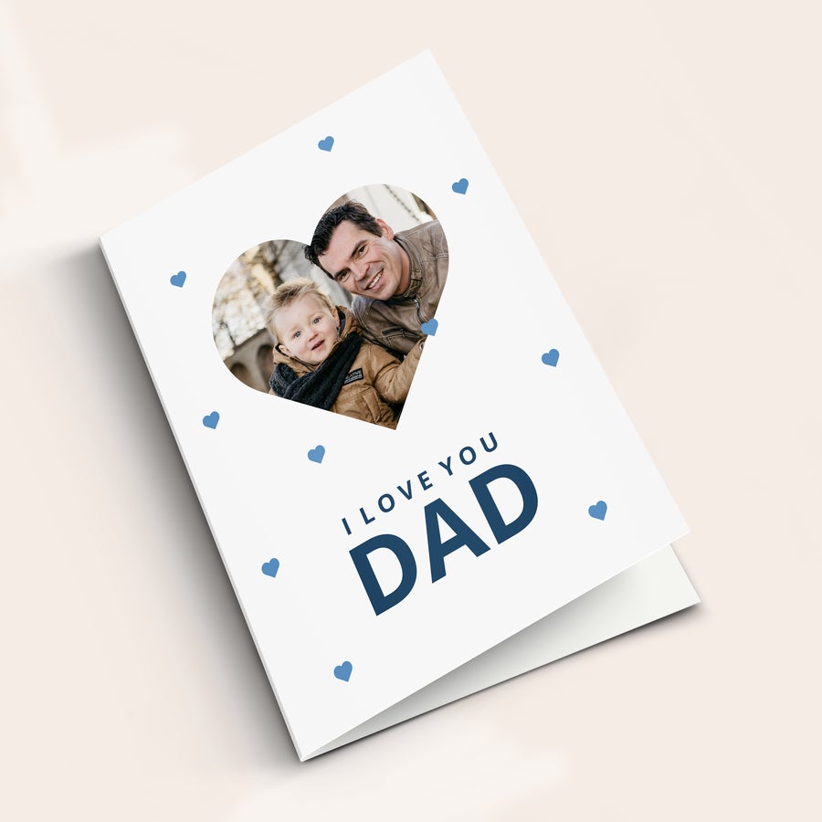 Egy kártya apának Fehér, szív alakú fényképpel nyomtatott Apák napja üdvözlőkártya, "I LOVE YOU DAD" felirattal és kék szívekkel díszítve