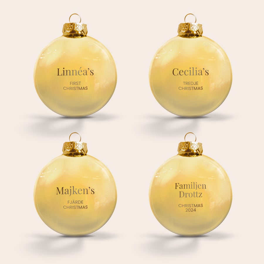 Glasjulkulor med namn Fyra personliga graverade julgranskulor i glas, med namn och text som Linnéa's First Christmas och Familjen Drottz Christmas 2024.