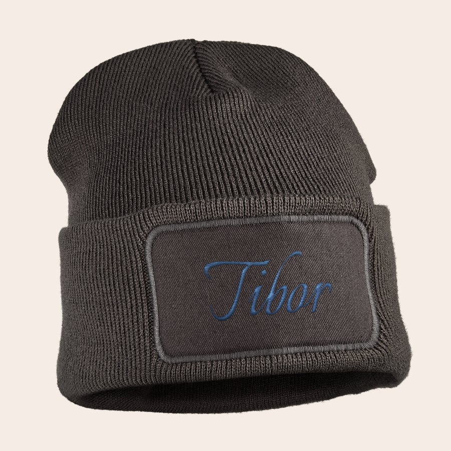 Hímzett kalap Sötétszürke sapka hímzett névvel (Tibor) egy pamutdarabon, ami kedves és melegen tartja ezeket a kis füleket.