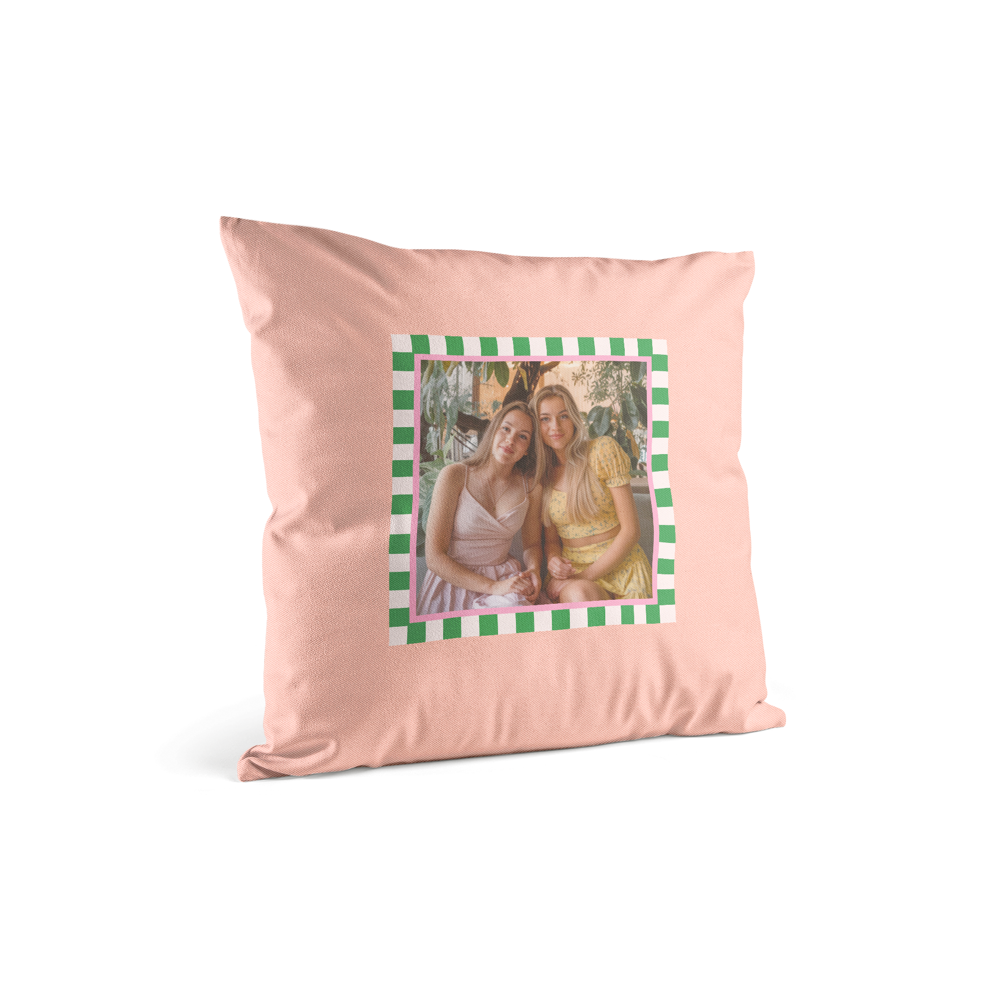 Ein super weiches Kissen mit Foto von zwei lachenden jungen Frauen, umrandet von einem pink-grünen Schachbrettmuster.