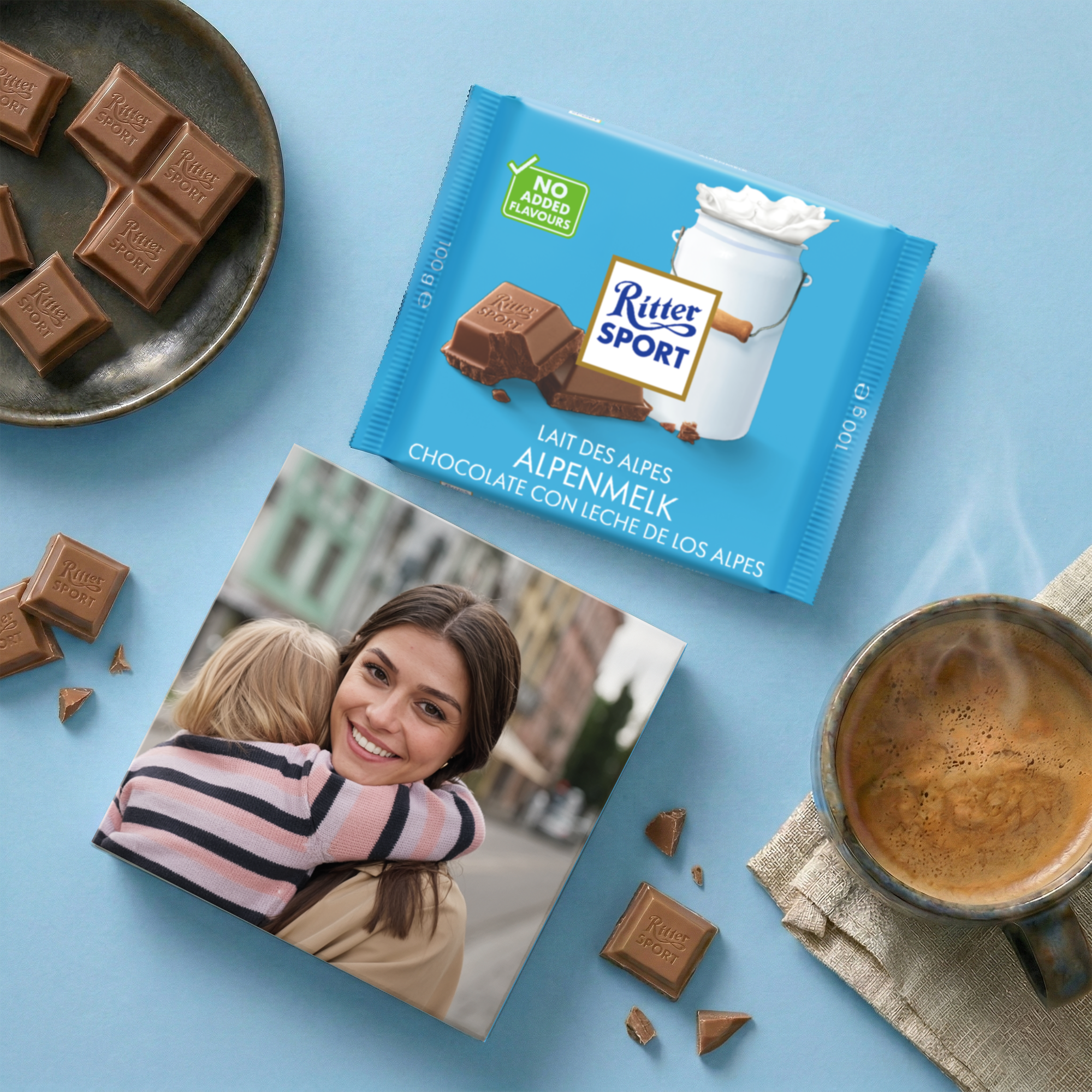 Chocolate Ritter Sport personalizado Alpine Milk impreso con tu foto junto a pastillas de chocolate y una taza de café