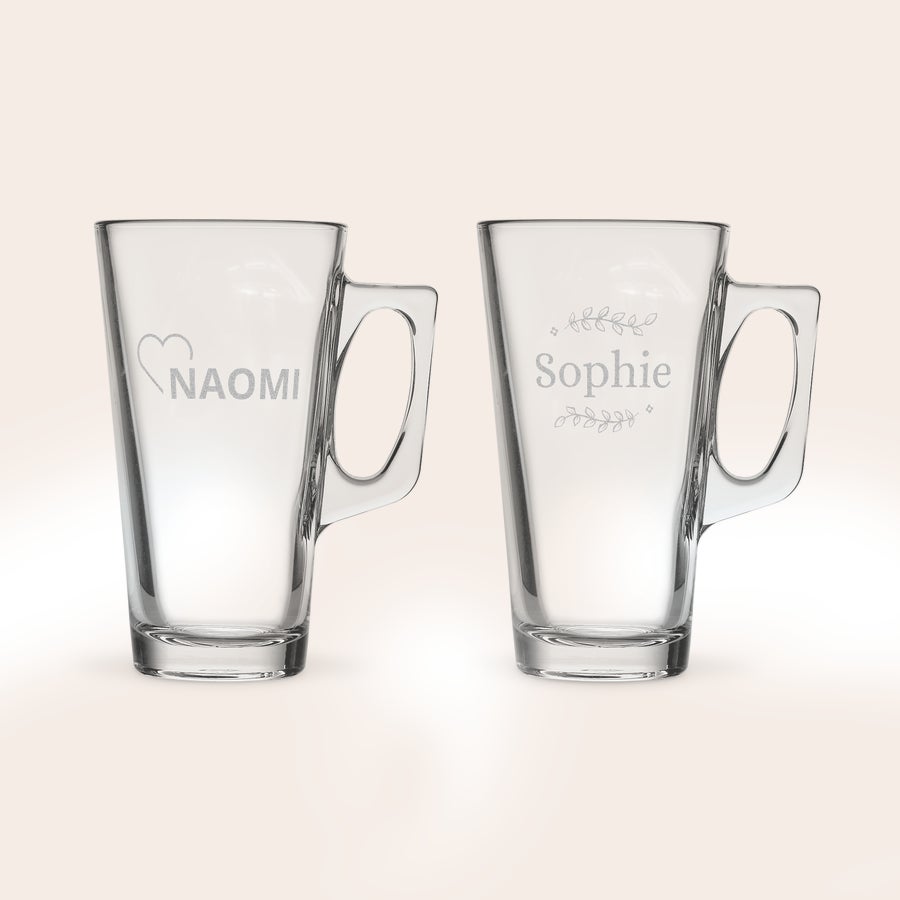 Latte macchiato glas graveren Twee gepersonaliseerde latte macchiato glazen, één gegraveerd met "NAOMI" en hartje, de ander met "Sophie" en bloemblaadjes.