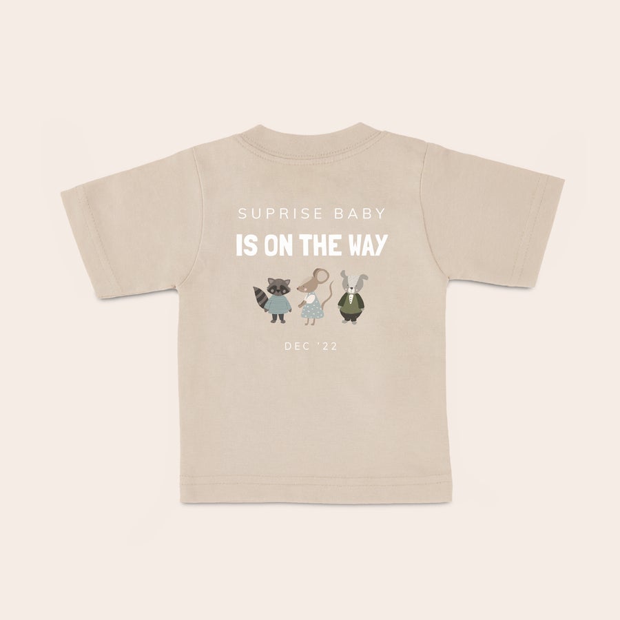 Maglietta del bambino Maglietta personalizzata per neonato beige con stampa "SUPRISE BABY IS ON THE WAY", tre animali del bosco e data 'DEC '22'.