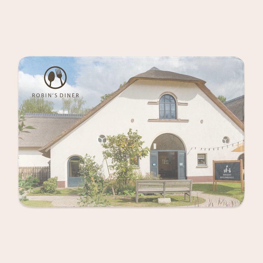 Personalised photo blanket A personalized fleece photo blanket printed with an image of a white building with a thatched roof and Robin's Diner logo.