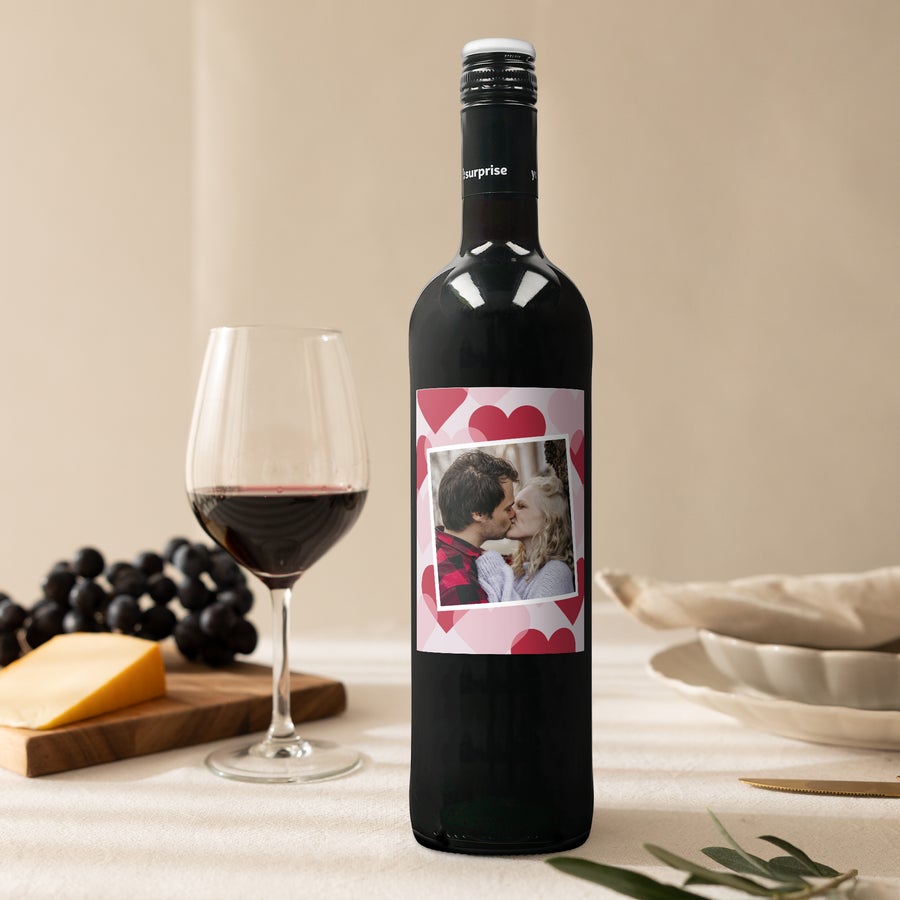 Maison de la Surprise Merlot Sticlă de vin Luc Pirlet cu etichetă personalizată cadou, imprimată cu o poză romantică, înconjurată de inimi roșii.