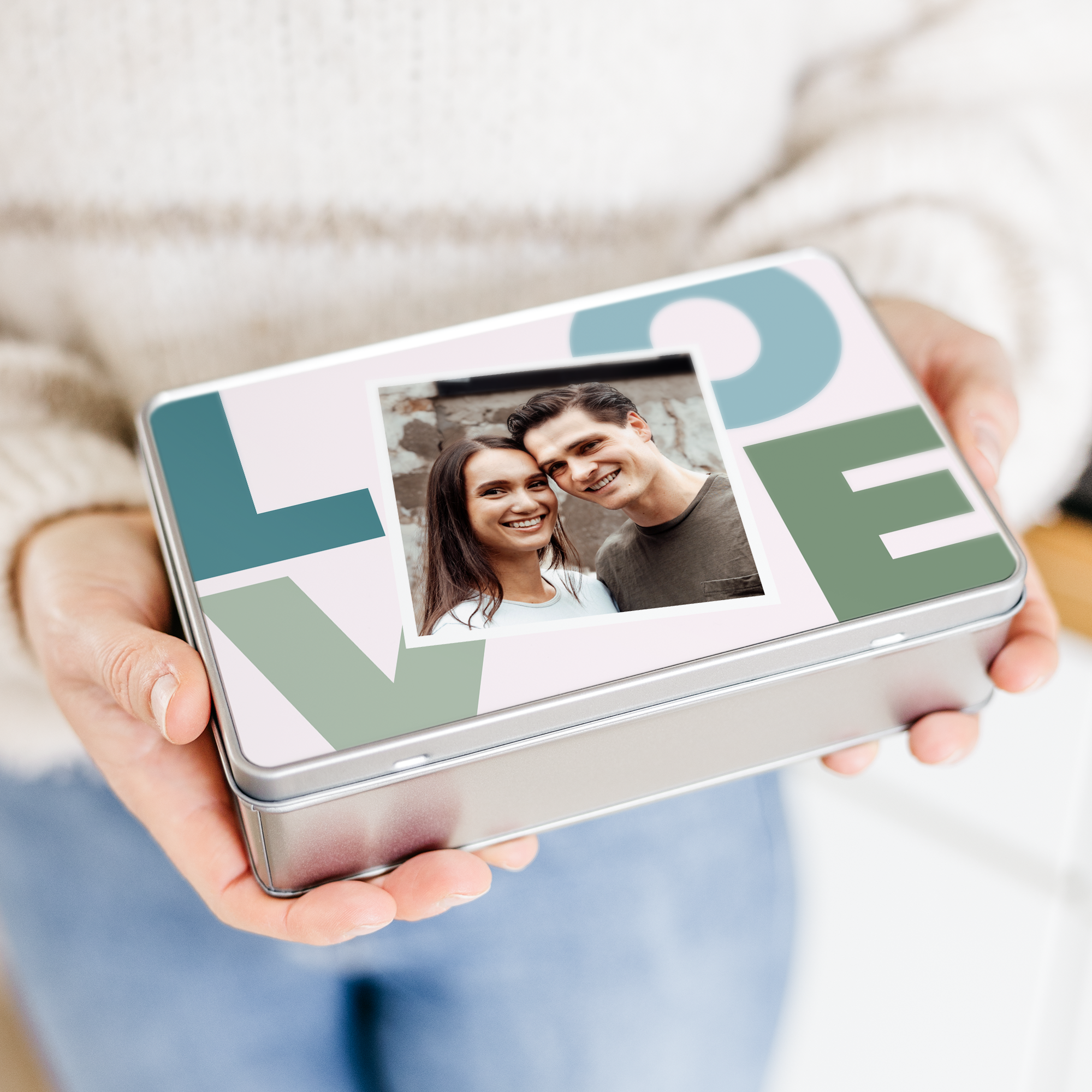 Blikkboks med foto, der "LOVE" er trykt i store bokstaver og et par smiler.