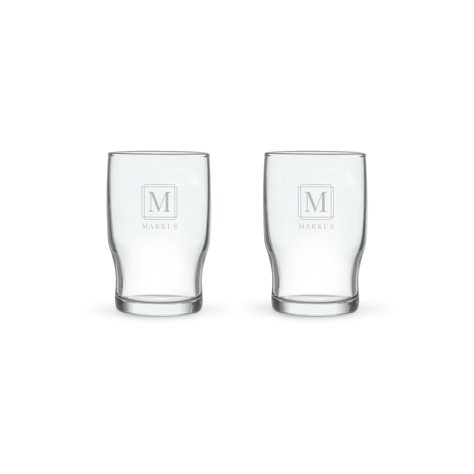 Två personliga vattenglas, lasergraverade med bokstaven M och namnet Markus. Ett glas vatten smakar bättre i ett personligt vattenglas.