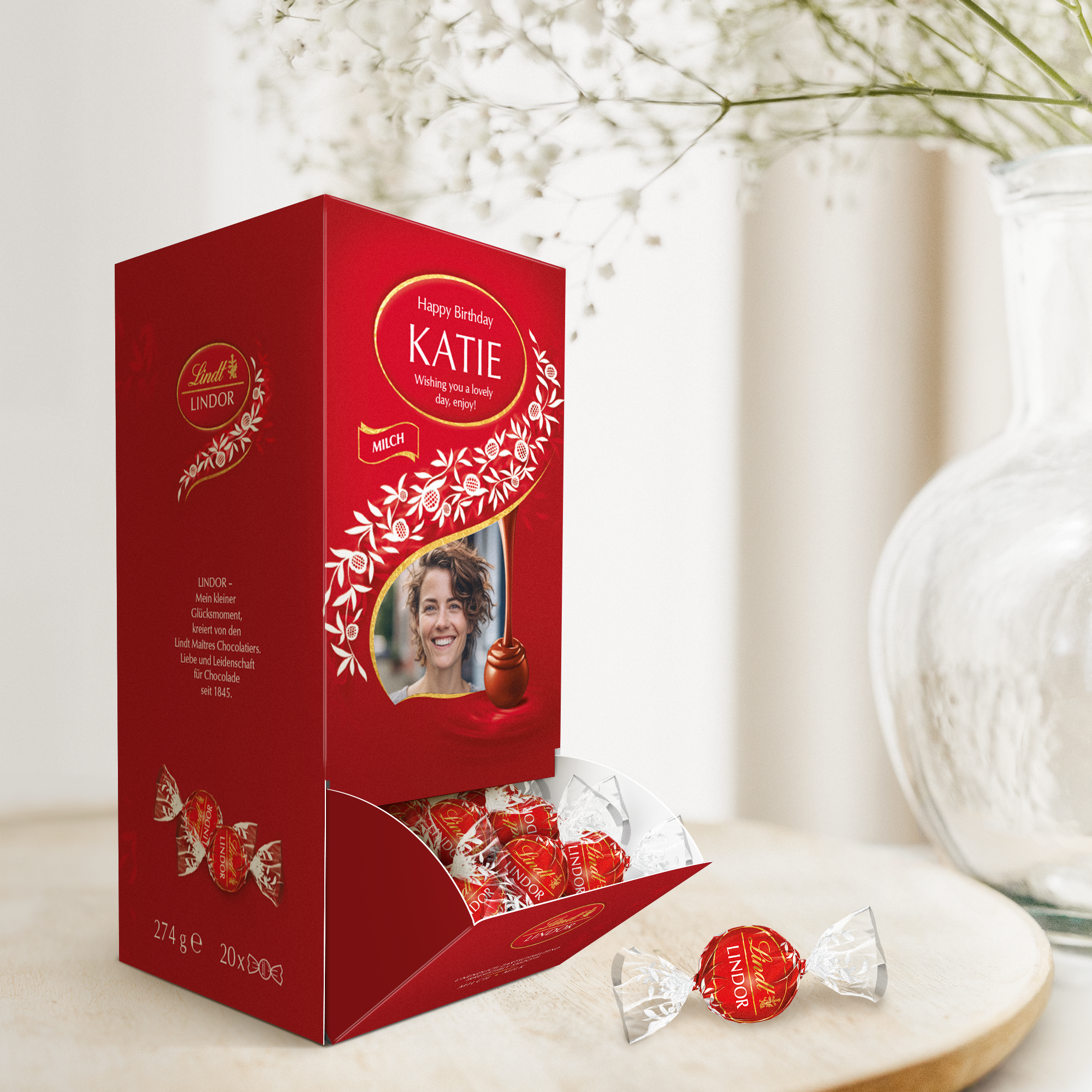 Cutie cadou personalizata de ciocolata Lindt, rosie, imprimata cu fotografie si text "Happy Birthday Katie", cu bomboane Lindor la vedere.
