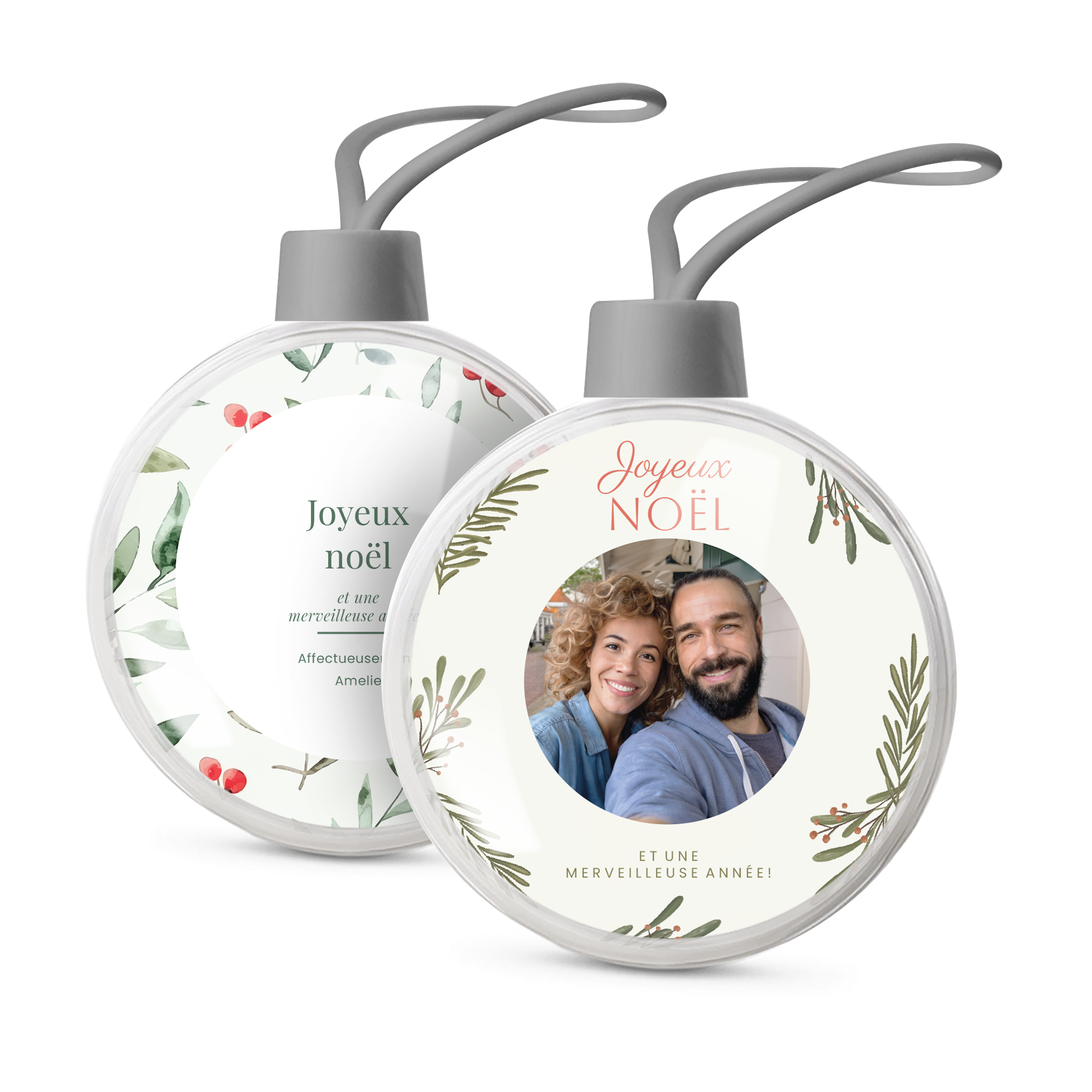 Deux boules de Noël transparentes personnalisées avec photo et message Joyeux Noël et Amelie, décorées de houx pour un sapin unique.