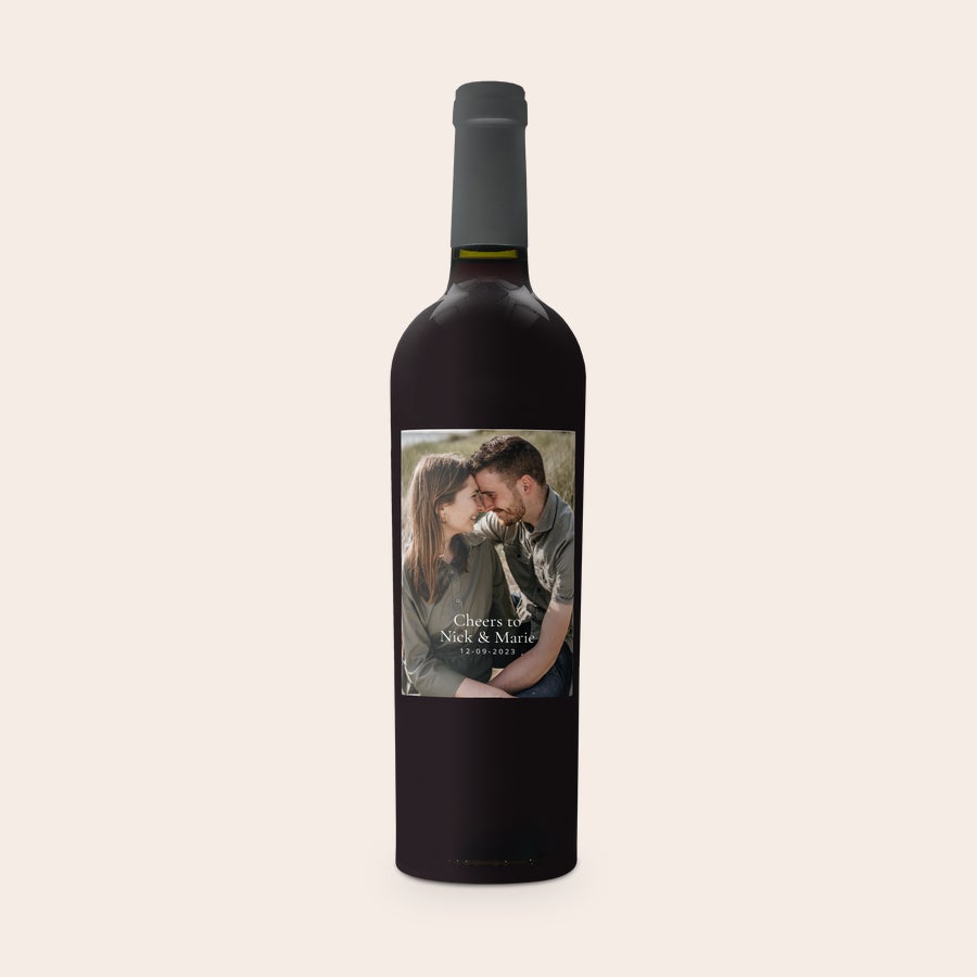Riondo Merlot Sticlă de vin Riondo Merlot cu etichetă personalizată, imprimată cu fotografia unui cuplu și textul Nick & Marie, 12-09-2023.