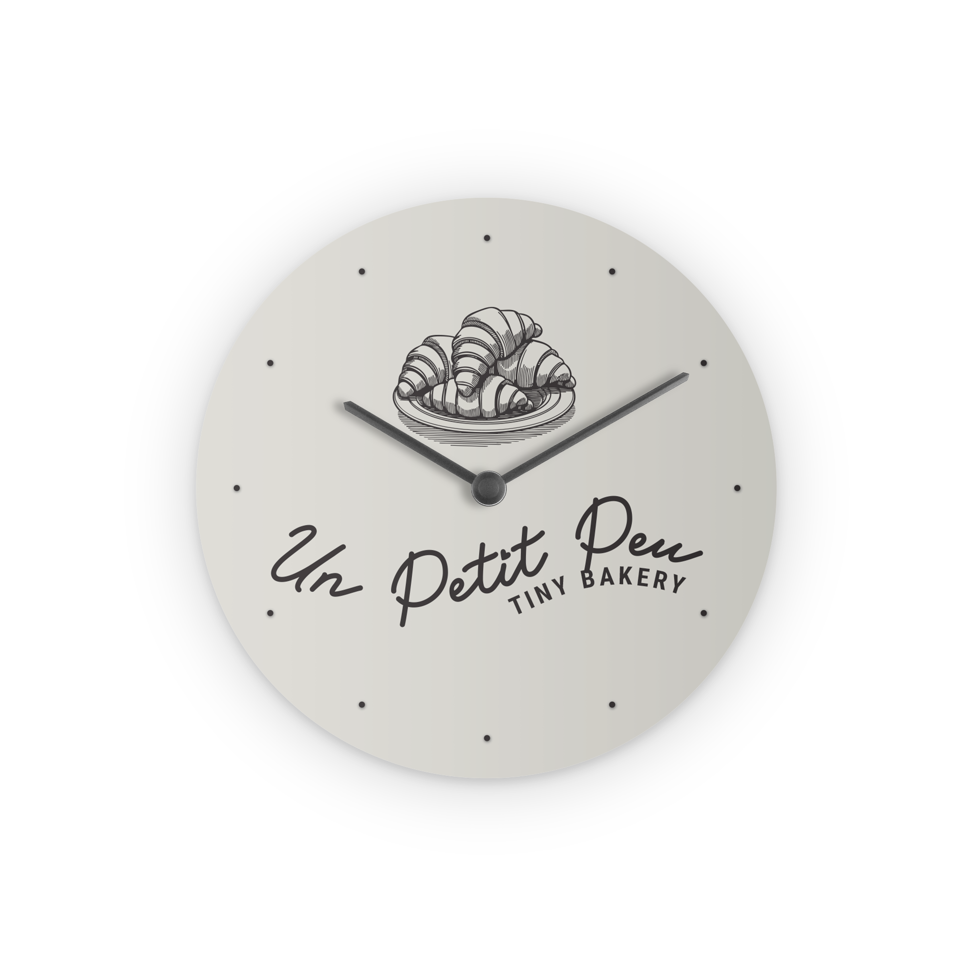 Round personal clock with a bakery logo printed with a photo of croissants and Un Petit Peu Tiny Bakery text