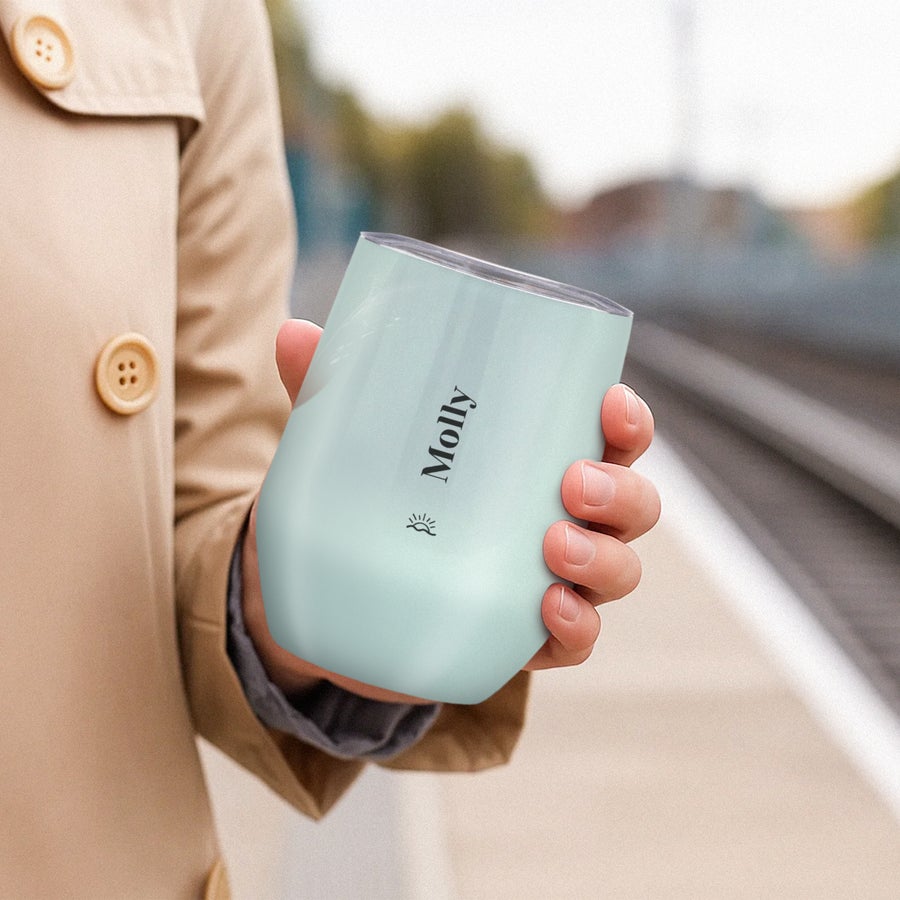 Resemugg med lock Mintgrön personlig resemugg med texten Molly och en sol tryckt i svart, hållen i en hand.