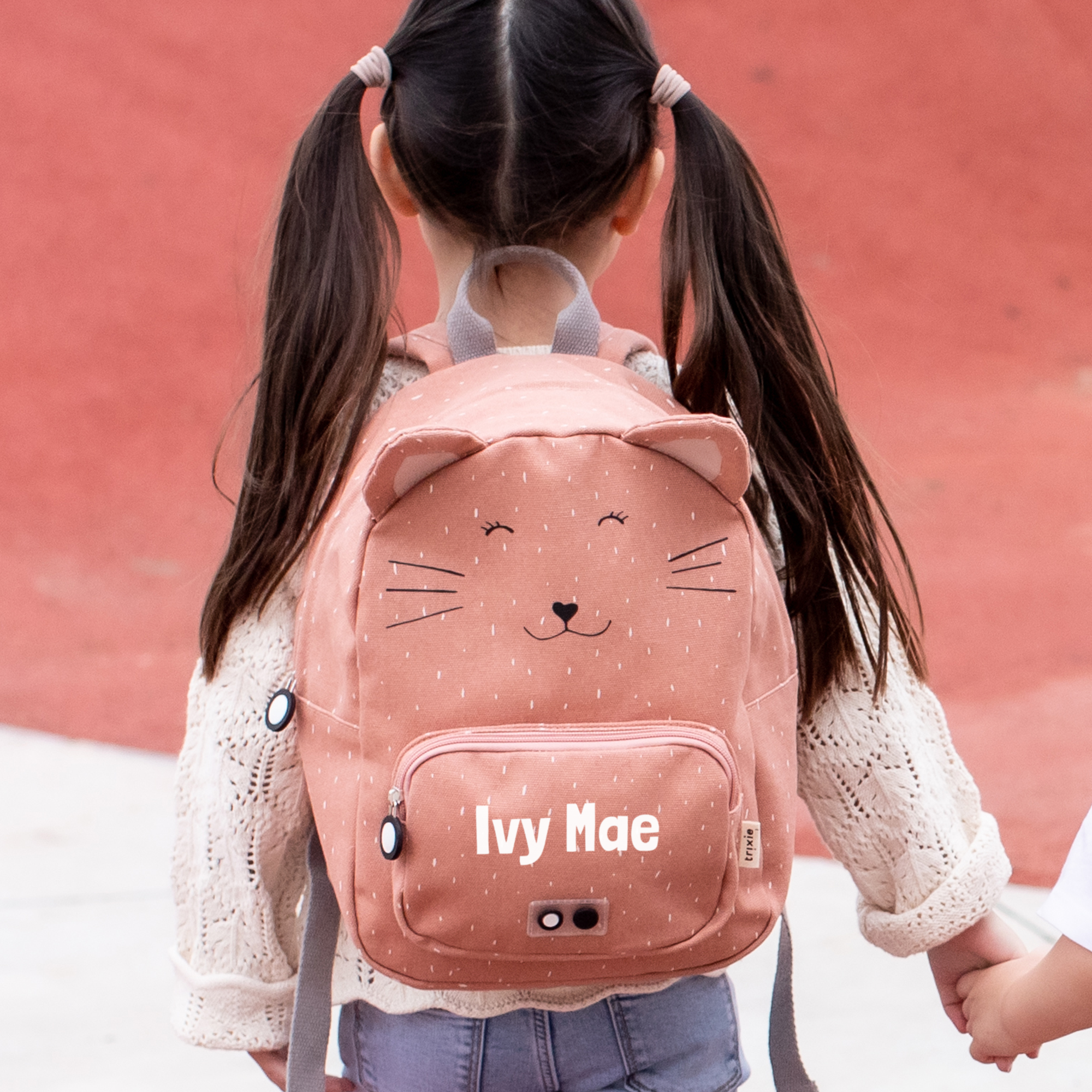 Bambina con zaino per bambini rosa a forma di gatto, personalizzato con il nome Ivy Mae stampato sul davanti