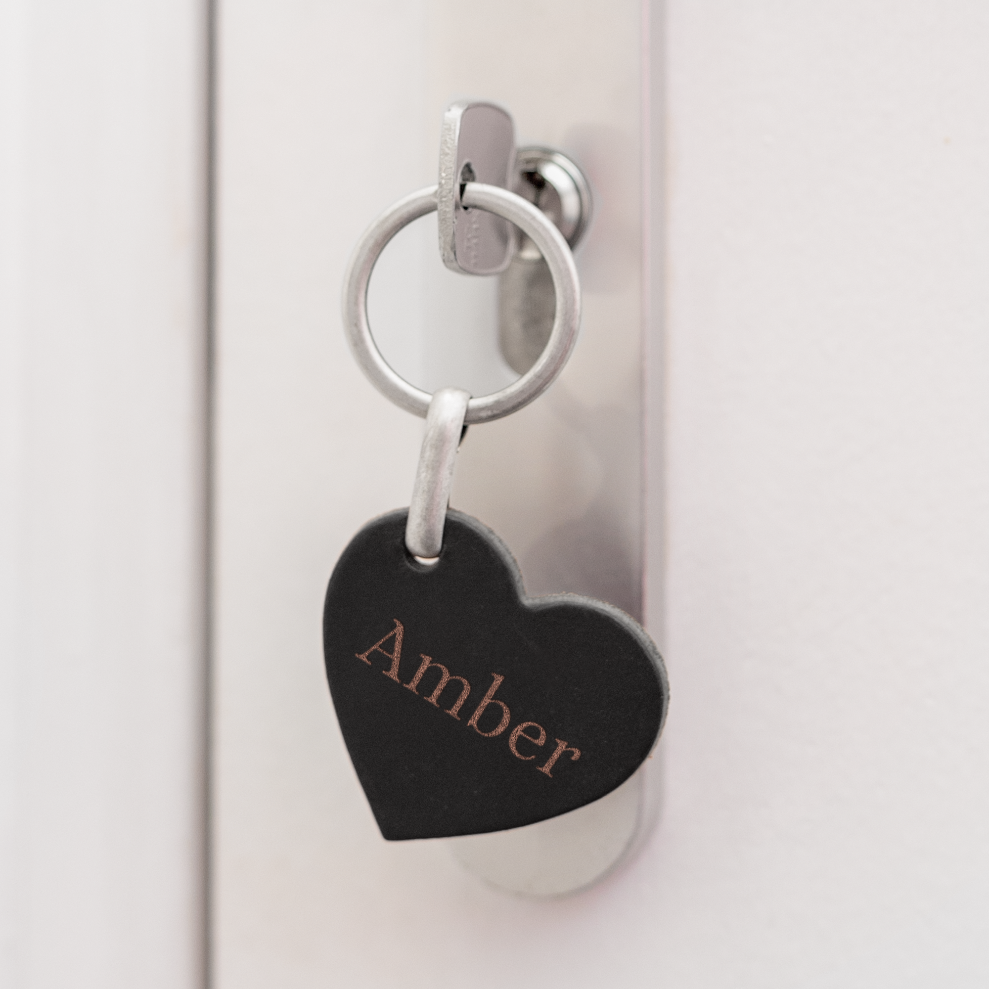 En personlig hjerteformet lædernøglering graveret med navnet "Amber" i brunt.