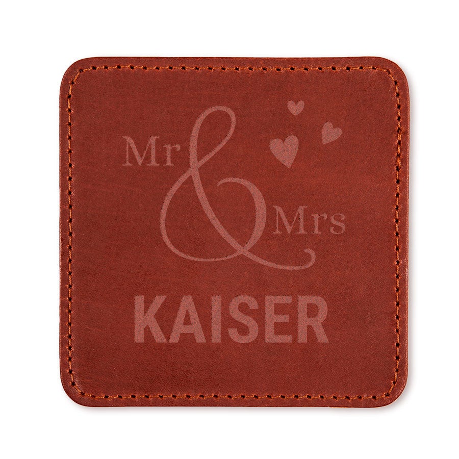 Brauner Lederuntersetzer mit Mr & Mrs, einem großen stilisierten "&" Zeichen, kleinen Herzen und dem Namen Kaiser, laser-graviert