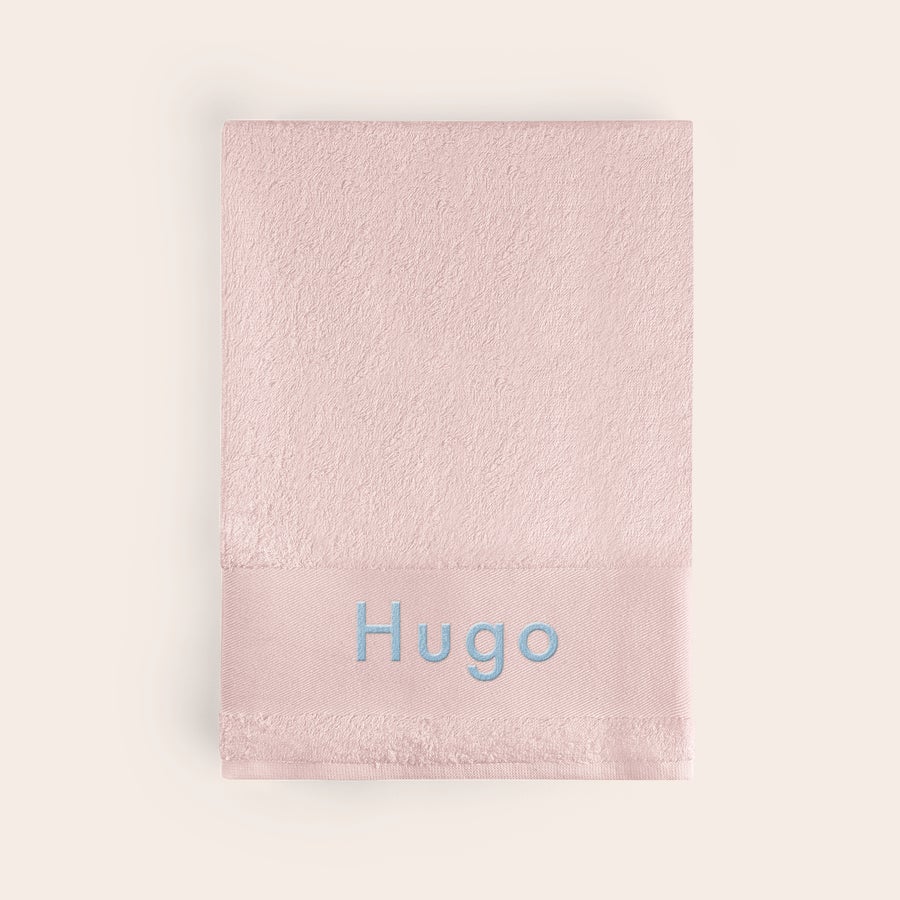 Serviette brodée Serviette rose personnalisée avec le prénom Hugo brodé en bleu ciel, une touche unique pour le bain.