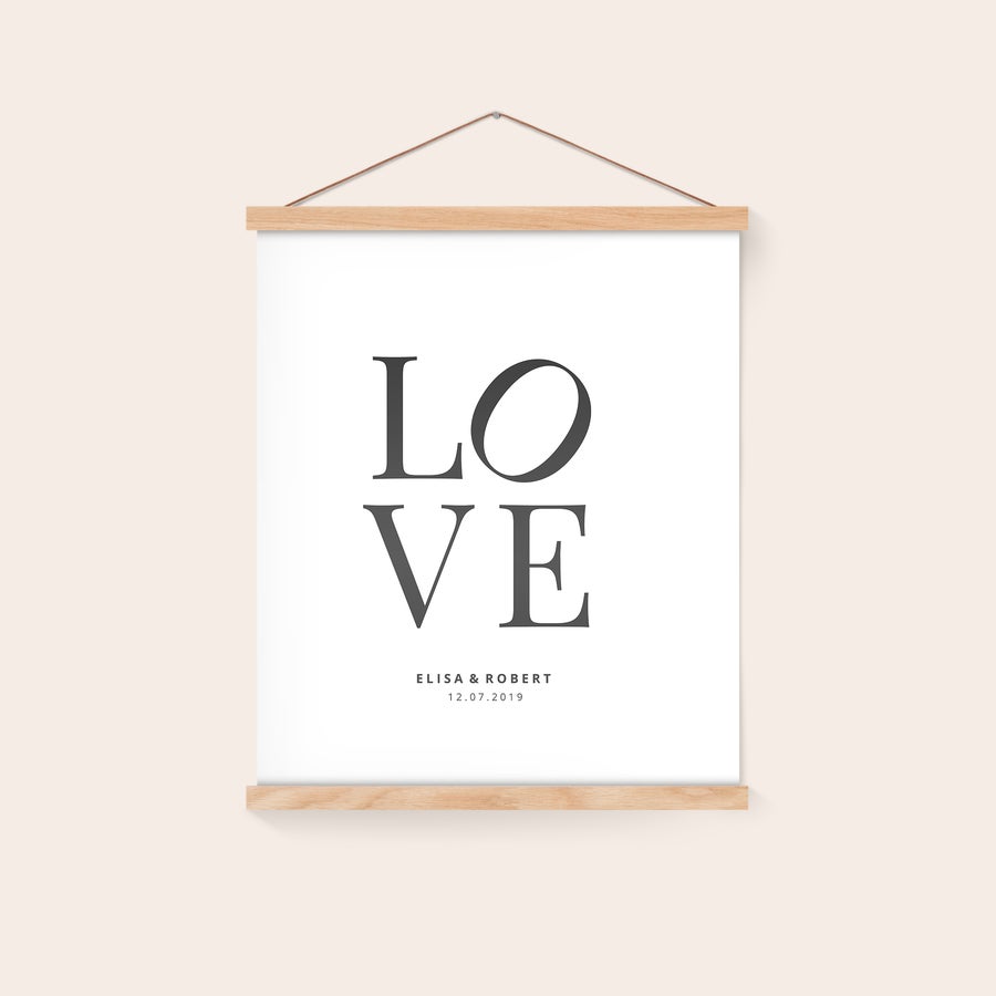 Poster personaliseren met posterhanger Gepersonaliseerde poster met "LOVE", namen "ELISA & ROBERT" en datum "12.07.2019" geprint aan een magnetische posterhanger van eikenhout.